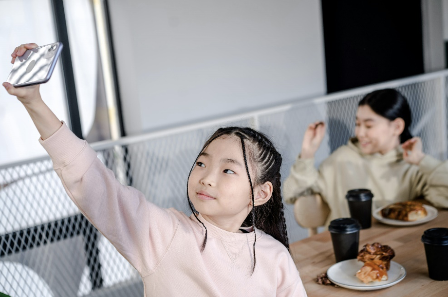 Young girl using her phone on the breakfast table 