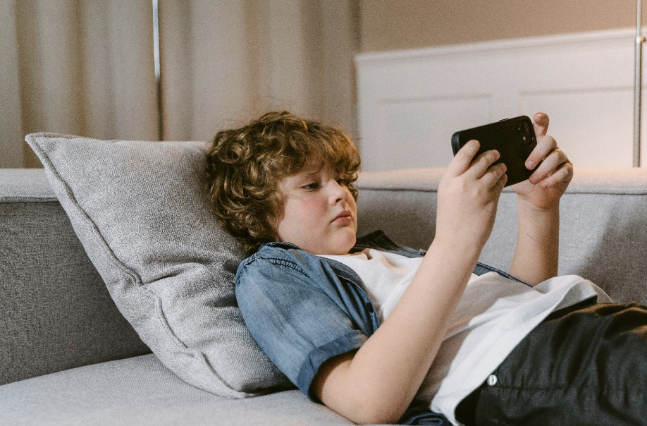 A young boy using a cell phone on a sofa